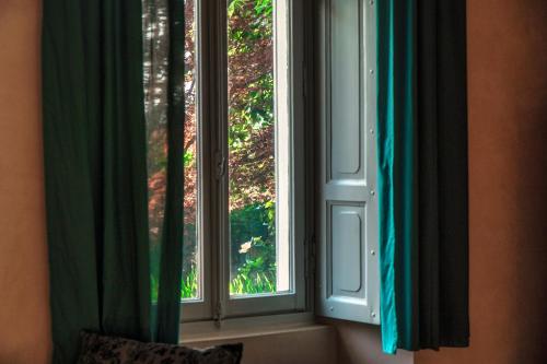 two windows with green curtains in a room at Dandelion Como Suites & Park in Villa Guardia