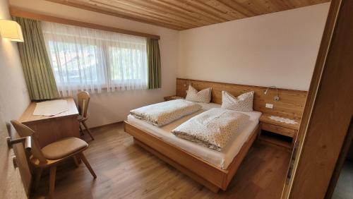 1 dormitorio con cama, escritorio y silla en Apartments Ingrid, en La Valle