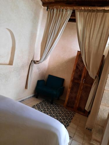 a bedroom with a bed and a blue chair at Dar Halima in Essaouira