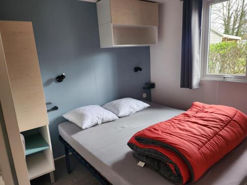 - un lit avec une couverture rouge dans l'établissement camping les pêcheurs, à Pont-de-Poitte