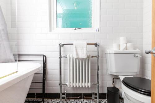 a white bathroom with a toilet and a radiator at GuestReady - Uma joia escondida em Brighton in Brighton & Hove