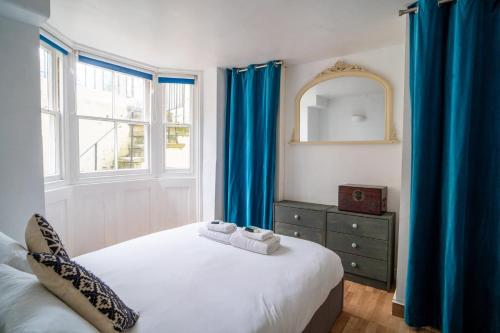 una camera da letto con un letto con tende blu e uno specchio di GuestReady - One lovely experience in Brighton a Brighton & Hove