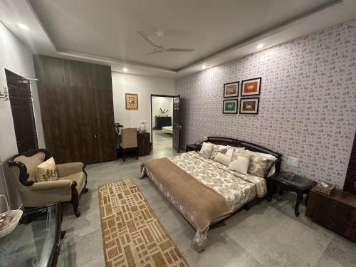 a bedroom with a bed and a couch and a chair at Luxurious Farmhouse with Pool outside Delhi in Noida