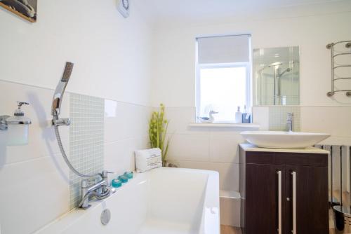 a white bathroom with a sink and a tub and a sink at GuestReady - Refúgio à beira-mar com terraço in Brighton & Hove
