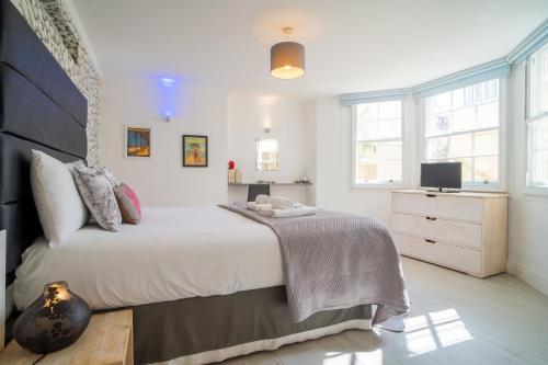 a white bedroom with a large bed and a television at GuestReady - Refúgio à beira-mar com terraço in Brighton & Hove