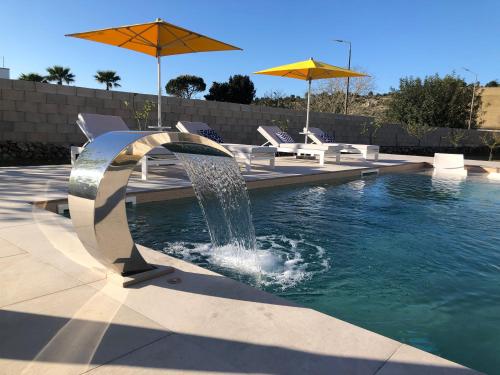 une fontaine dans une piscine avec des chaises et des parasols dans l'établissement CasaKarina - Villa con piscina privata, à Specchia