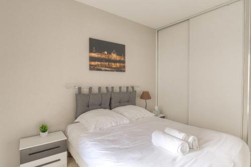 ein weißes Schlafzimmer mit einem großen Bett mit weißer Bettwäsche in der Unterkunft Fonctionnel et Calme avec parking gratuit in Villeurbanne