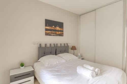a white bedroom with a large bed with white sheets at Fonctionnel et Calme avec parking gratuit in Villeurbanne