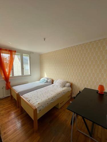 une chambre avec deux lits et une table dans l'établissement Maison Quartier de Pors Carn, à Penmarcʼh
