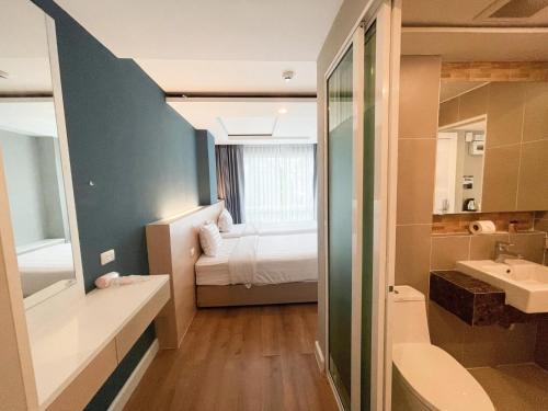 a bathroom with a bed and a sink and a mirror at Wisdom Hotel & Residence in Rayong