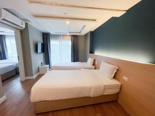 a hotel room with two beds and a green wall at Wisdom Hotel & Residence in Rayong