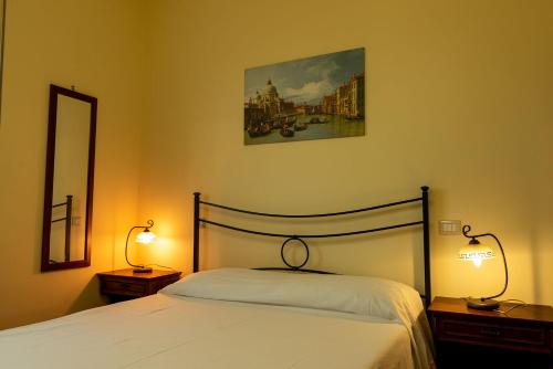 ein Schlafzimmer mit einem Bett mit zwei Lampen und einem Spiegel in der Unterkunft Appartamento Locazione Turistica L'Antica Sorgente Panicale in Panicale