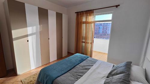 a bedroom with a bed and a large window at Appartamento Bruno spazioso e centrale in Shkodër