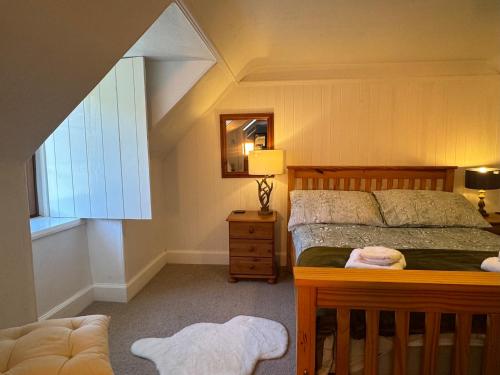 een slaapkamer met een bed, een stoel en een raam bij Rosemount Cottage ONE- Highland Cottage in Garve