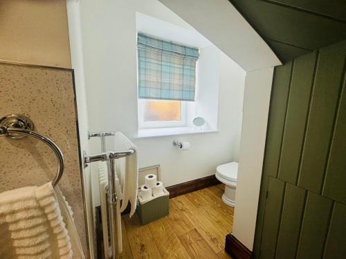een badkamer met een douche, een toilet en een raam bij Rosemount Cottage ONE- Highland Cottage in Garve