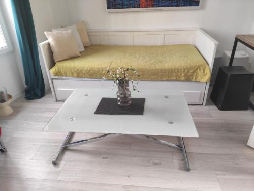 a white table with a vase of flowers on it at Appartement paisible in Clichy