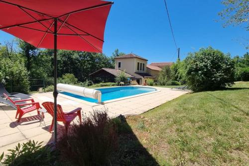 una sombrilla roja sentada junto a una piscina en Maison Spacieuse situation idéale au calme en Bouillac