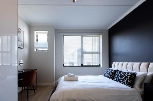 a bedroom with a white bed and two windows at City Nest:Heart of Linksfield II in Johannesburg