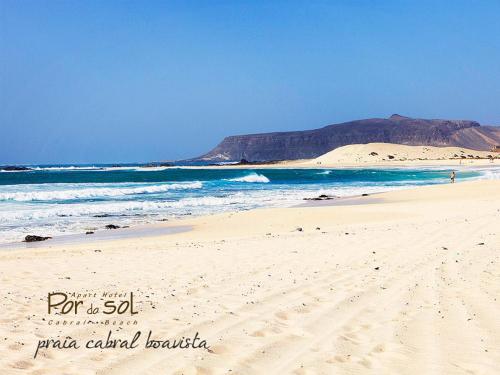 a beach with the ocean and a mountain in the background at Aparthotel Por do Sol in Sal Rei