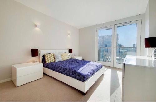 a white bedroom with a bed and a large window at O2 Greenwich Central City Stays in London