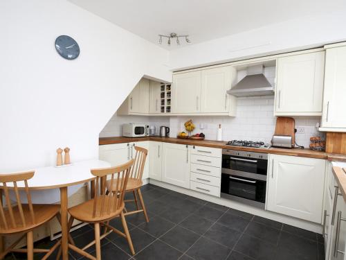 a kitchen with white cabinets and a table and chairs at Sunny Victorian 2BR Townhouse Oxford - Pass the Keys in Oxford