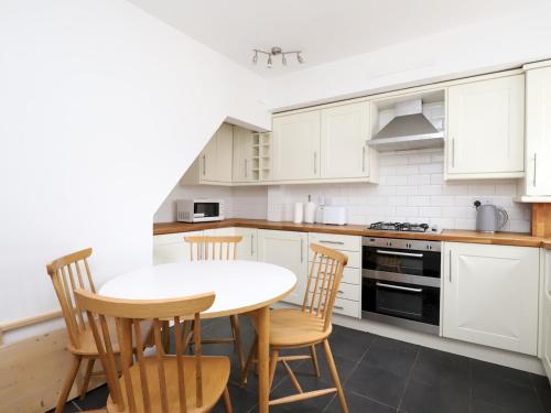 a kitchen with white cabinets and a table and chairs at Sunny Victorian 2BR Townhouse Oxford - Pass the Keys in Oxford