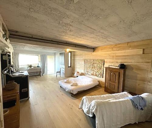 1 dormitorio con 2 camas en una habitación con paredes de madera en Commanderie Vue Panoramique 2 chambres en Le Poët-Laval