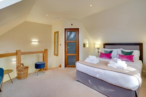 1 dormitorio con 1 cama grande con almohadas rosas en South Stable at Hallsteads: Cosy Stone Cottage, with Parking en Alnmouth