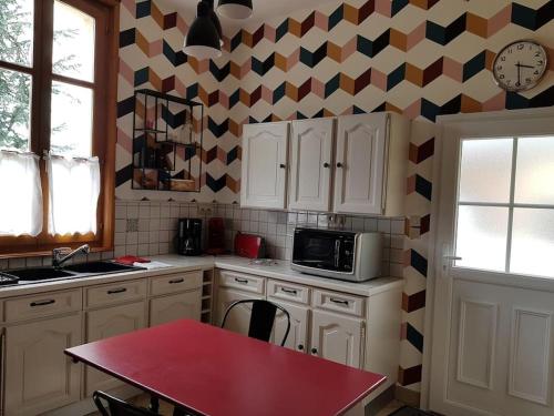 a kitchen with a red table and a microwave at Le Gîte d'en Bas in Quesnoy-le-Montant