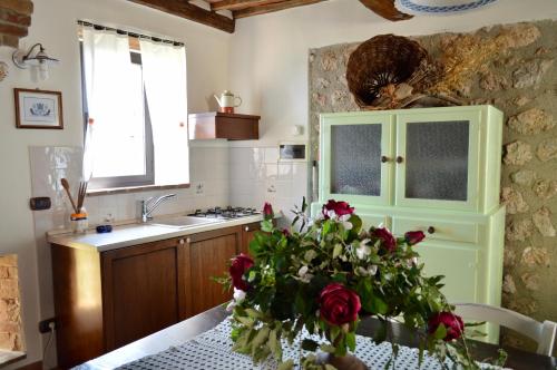 a kitchen with a table with a vase of roses at Agriturismo Il Caggio in Sovicille