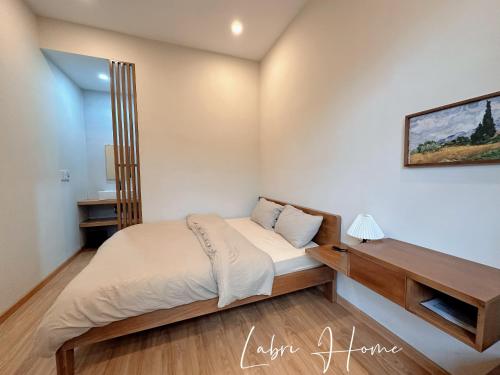 a small bedroom with a bed and a desk at Labri Home Da Lat in Da Lat