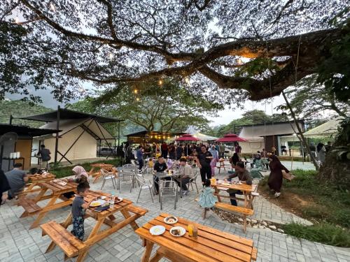 um grupo de pessoas sentadas em mesas em um parque em Glamping at Xscape Tambun em Tambun