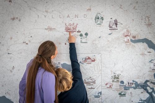 a woman is painting a wall with the word llandan at Kolding Hotel Apartments in Kolding