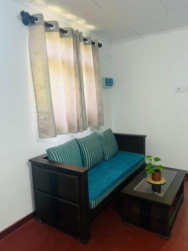 a living room with a blue couch and a table at Moon Bay in Mirissa