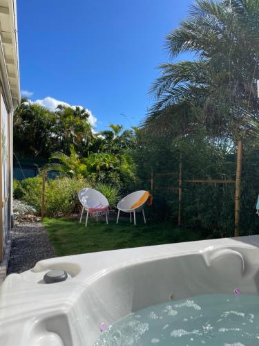 a bath tub in a yard with two chairs at Iguane House Villas & Micro Spa in Sainte-Anne