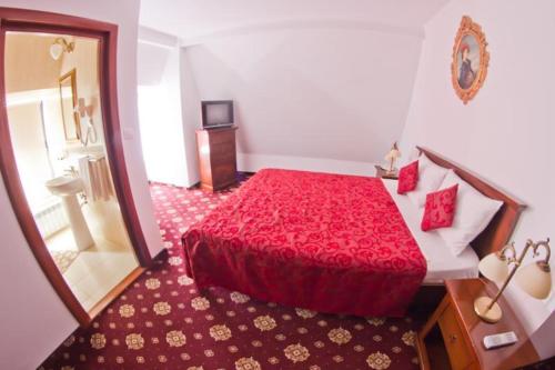 a bedroom with a red bed and a mirror at Vila Royal in Bacău