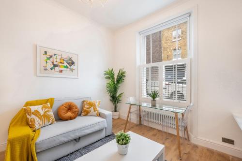 a living room with a couch and a table at Charming 1 Bedroom Flat with Private Patio - West London, Kensington, Earl's Court, Chelsea in London
