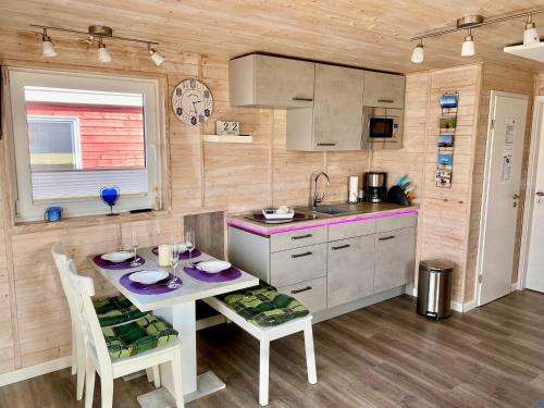 uma cozinha com uma mesa e cadeiras e um lavatório em Hausboot Lilla Lina em Fehmarn