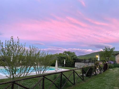 a fence next to a swimming pool with a sunset at Agriturismo Il Caggio in Sovicille