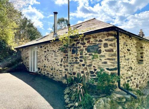 a stone house with a roof on the side of it at Chapel Barn in Bodmin