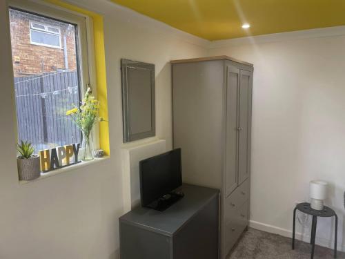 a room with a tv and a cabinet and a window at Single Room near Heathrow Windsor Legoland & Free Parking Onsite in Burnham