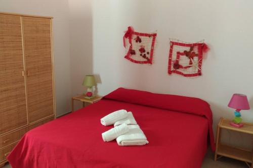 ein Schlafzimmer mit einem roten Bett mit Handtüchern darauf in der Unterkunft CAROSELLO in Torre San Giovanni Ugento