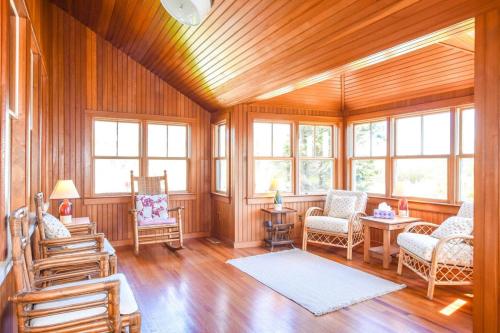 a living room with wood paneling and chairs and windows at Steps to Nauset Beach Private Yard in Orleans