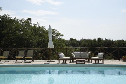 a group of chairs and an umbrella next to a pool at Agriturismo Il Caggio in Sovicille