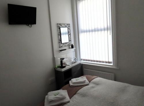 a bedroom with a bed and a mirror and a window at Willin House Hotel in Blackpool
