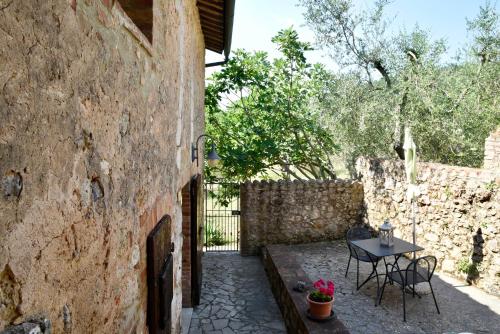 a patio with a table and chairs next to a stone wall at Agriturismo Il Caggio in Sovicille