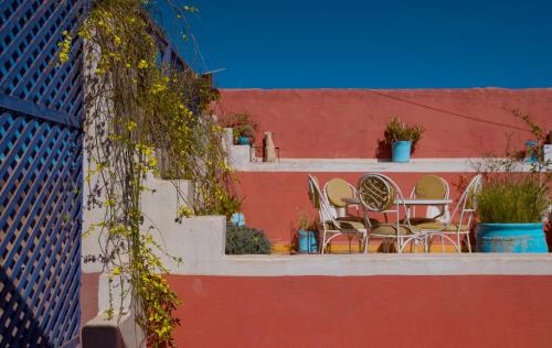 a patio with chairs and a table on a wall at Maison d'hôtes Dar Farhana in Ouarzazate