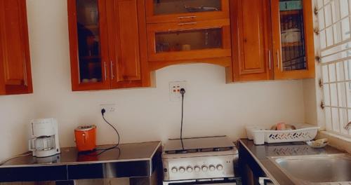 uma cozinha com armários de madeira e uma bancada em Sweet Home Buziga em Gaba