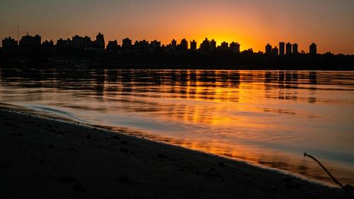 a city skyline at sunset over a body of water at La Casa de al Lado entre el centro y el río, la Mejor Ubicación en Paraná in Paraná