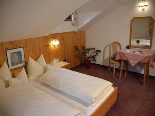 a bedroom with a large white bed and a table at Aparthotel Spitzer in Sankt Gallenkirch
